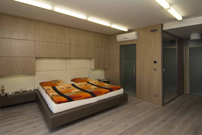 Atypické skříně v ložnici a netradičně řešená postel s koženým čalouněním